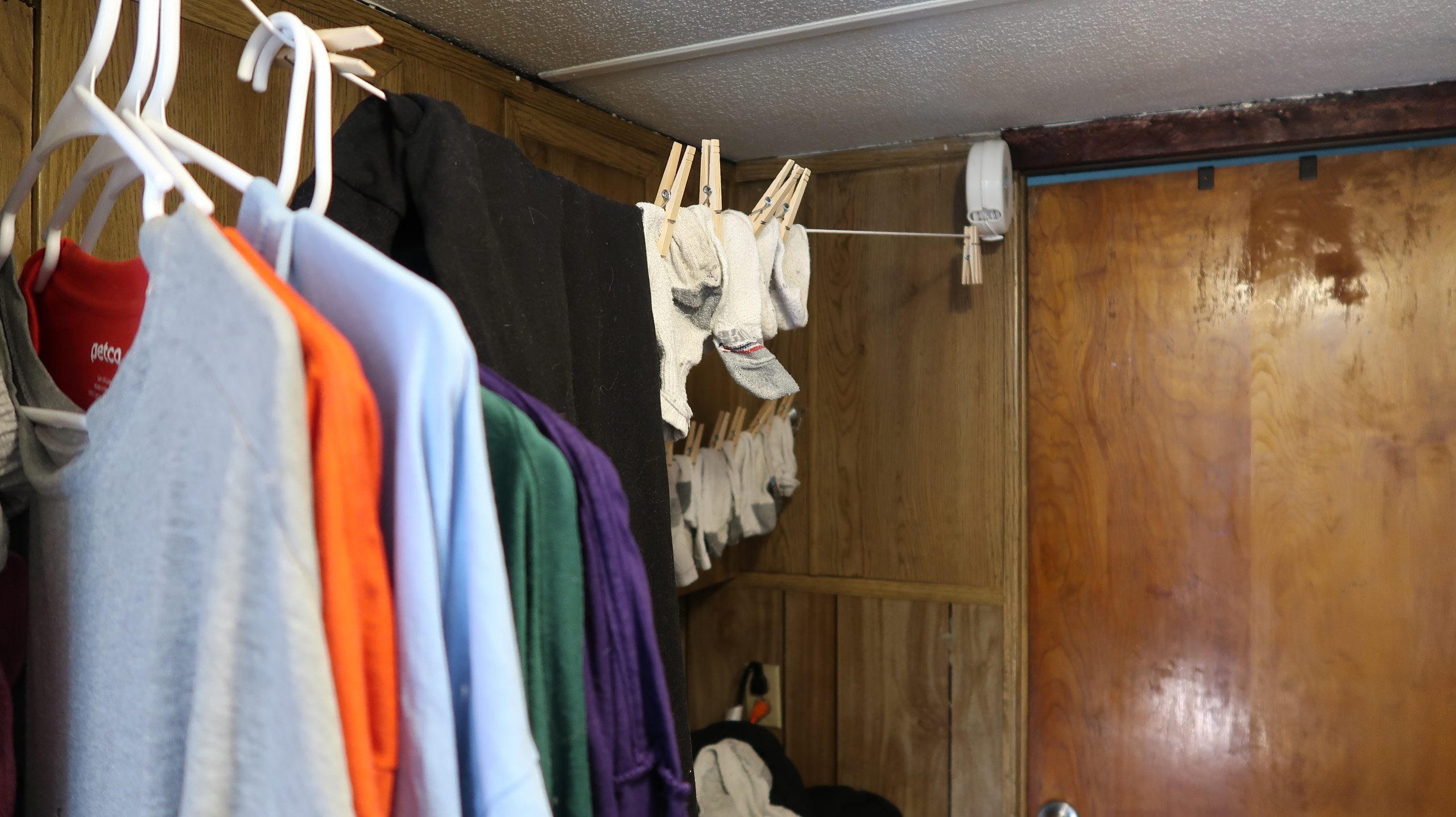 The image is of a clothesline in a small laundry room. Clothes are hanging on the line.